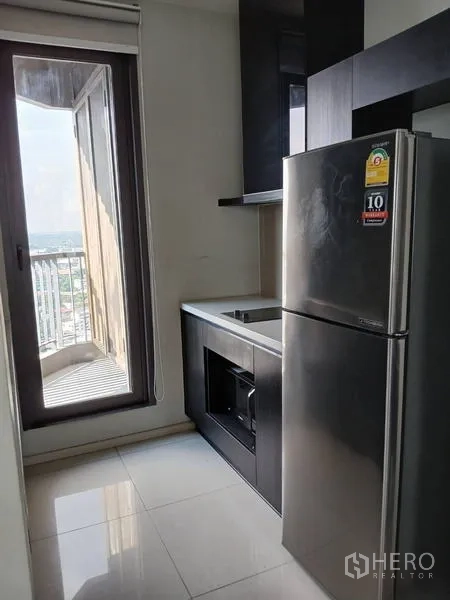 Condominium for rent - Galley kitchen with fridge, cooktop and oven leading to a balcony with city views.