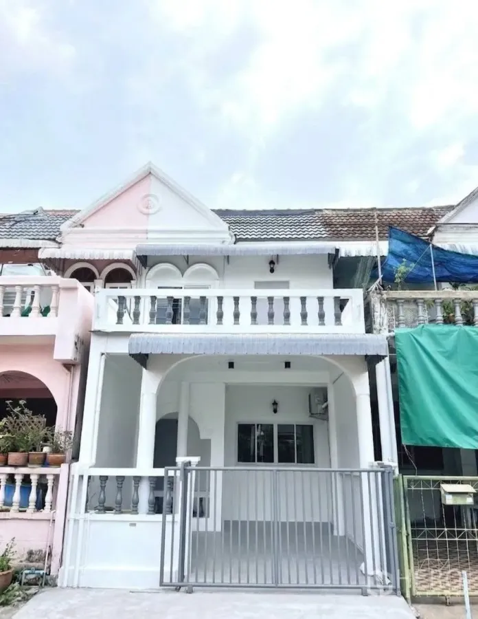ทาวน์เฮาส์ for rent in Phra Khanong, Bangkok - ด้านหน้าทาวน์เฮ้าส์สองชั้นโทนสีขาว มีระเบียงและประตูรั้วหน้าบ้าน.
