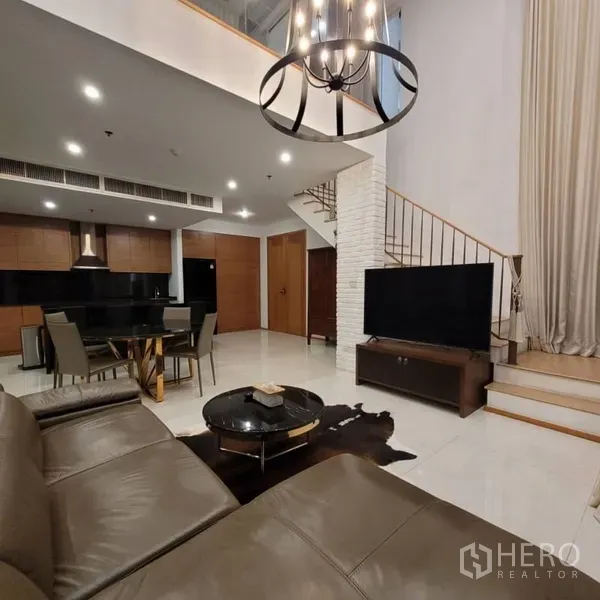 公寓 出租在Khlong Toei, Bangkok - 客厅配大屏电视与通往夹层的楼梯，后方为精致厨房。