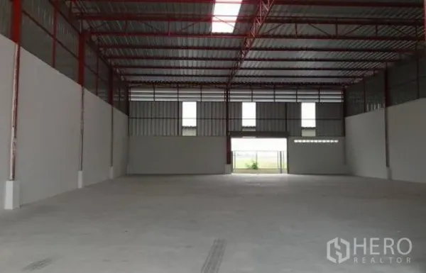 Factory for rent in Pathum Thani - Spacious empty factory floor with skylit roof and ventilation windows at both ends.