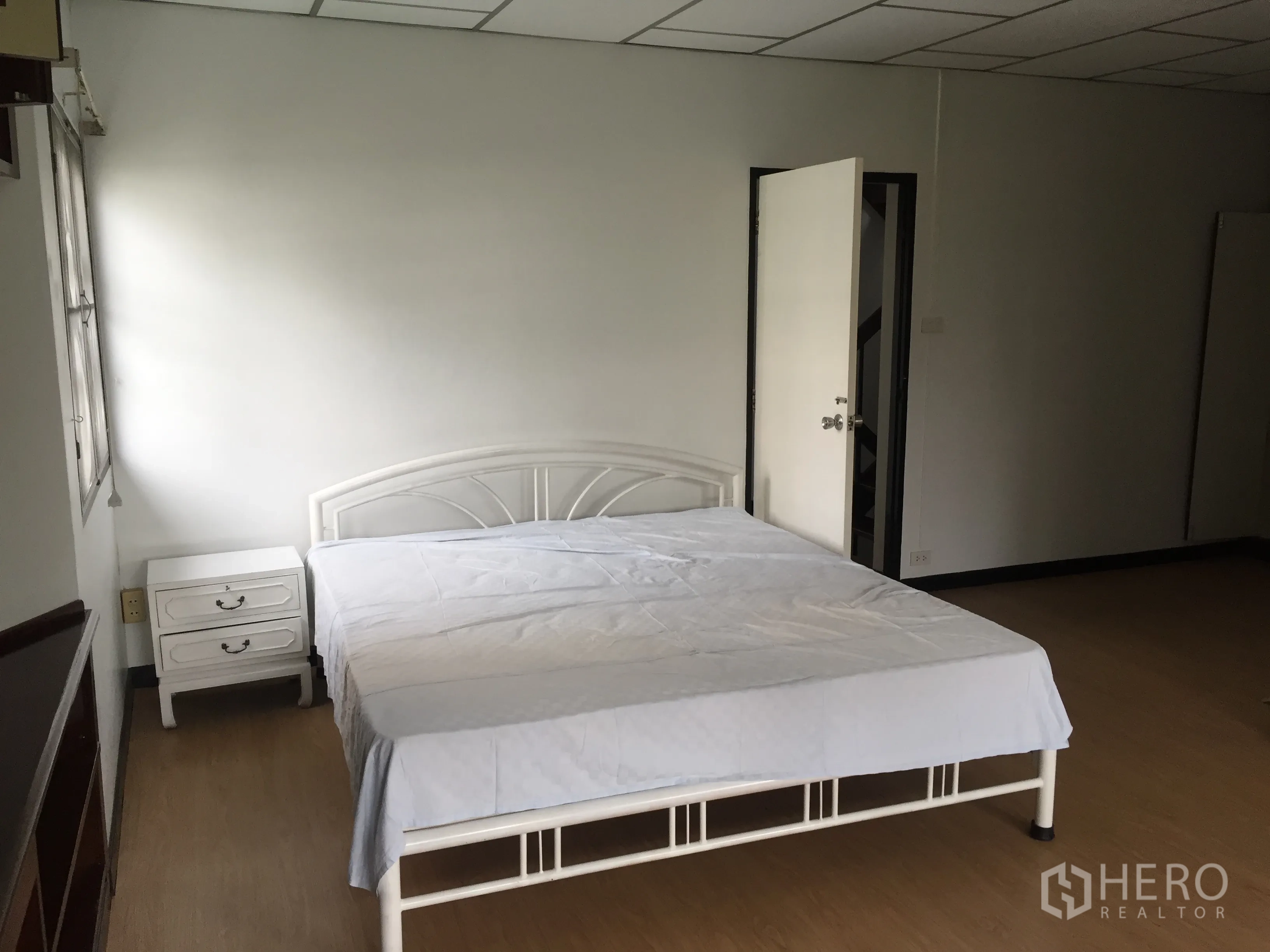 联排别墅 出租在Khlong Toei, Bangkok - 宽敞卧室，白色金属床与床头柜，木地板。