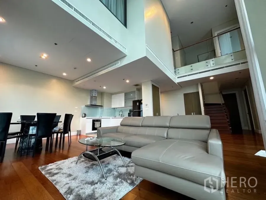 Condominium for rent in Khlong Toei, Bangkok - Another angle of the double-height living area with sectional sofa, rug and dining table.