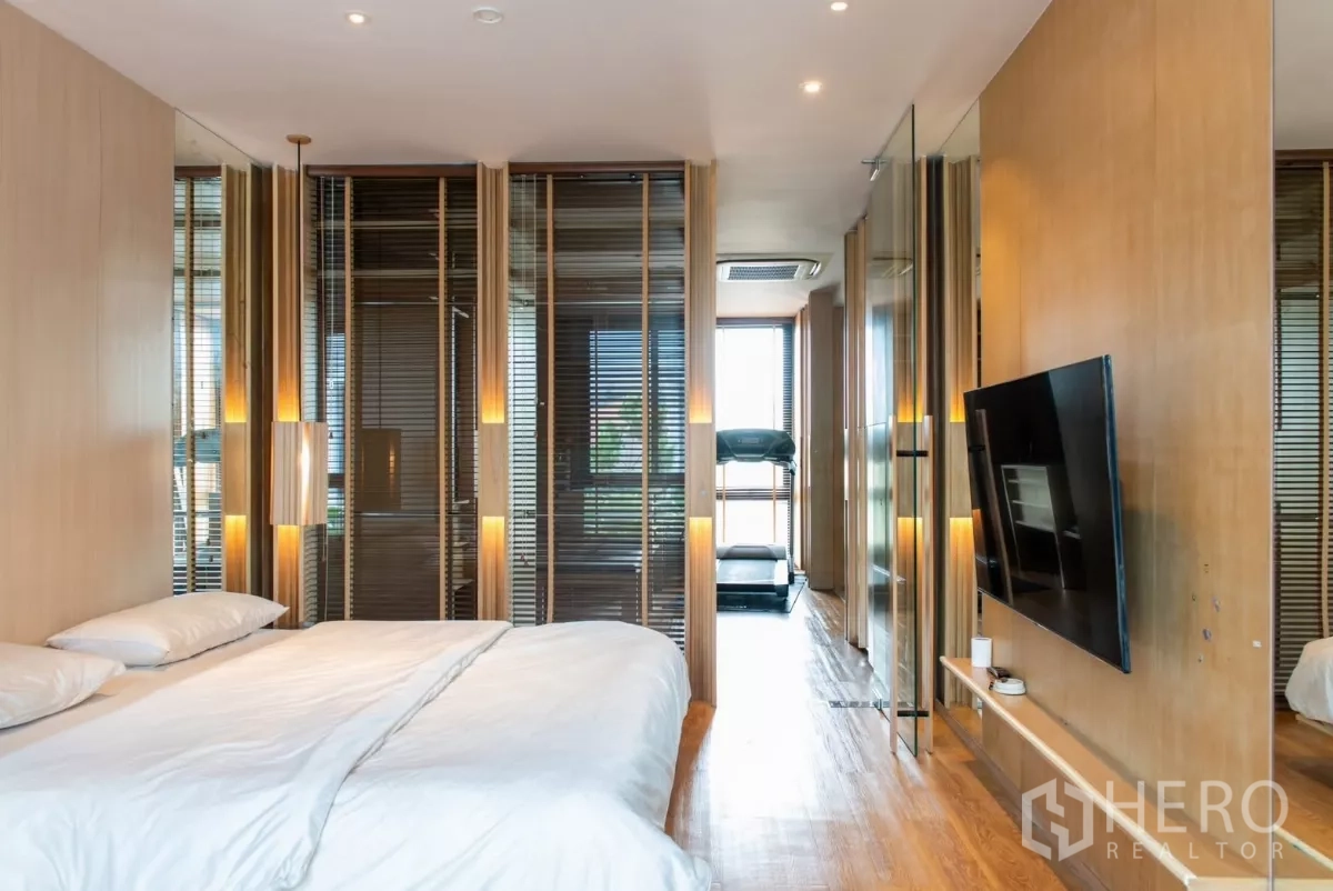 Townhouse for rent in Lat Phrao, Bangkok - Master suite corridor with bed, TV and a treadmill by the window.