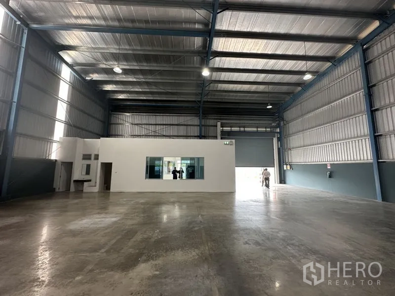 工厂 出租在Bang Phli, Samut Prakan - 开阔仓库空间，中央白色办公室盒体，明亮LED照明与大型卷帘门