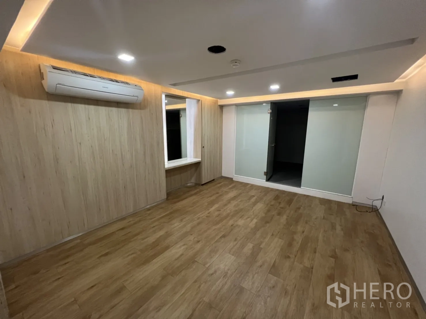 Shophouse for rent or sale in Watthana, Bangkok - Bright room with recessed lighting, frosted glass partition and wood-look floors.