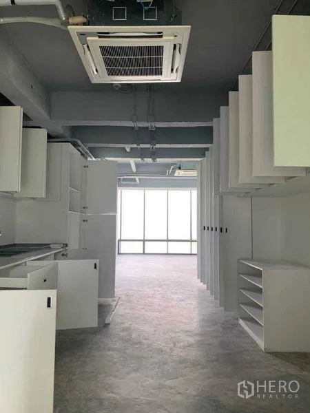Office Space for rent in Khlong Toei, Bangkok - Open-plan office with exposed ceiling, cassette air-conditioning and built-in white cabinetry.