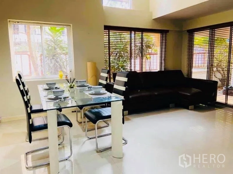 Detached House for rent in Watthana, Bangkok - Open-plan dining and lounge with corner sofa, window blinds and terrace access.