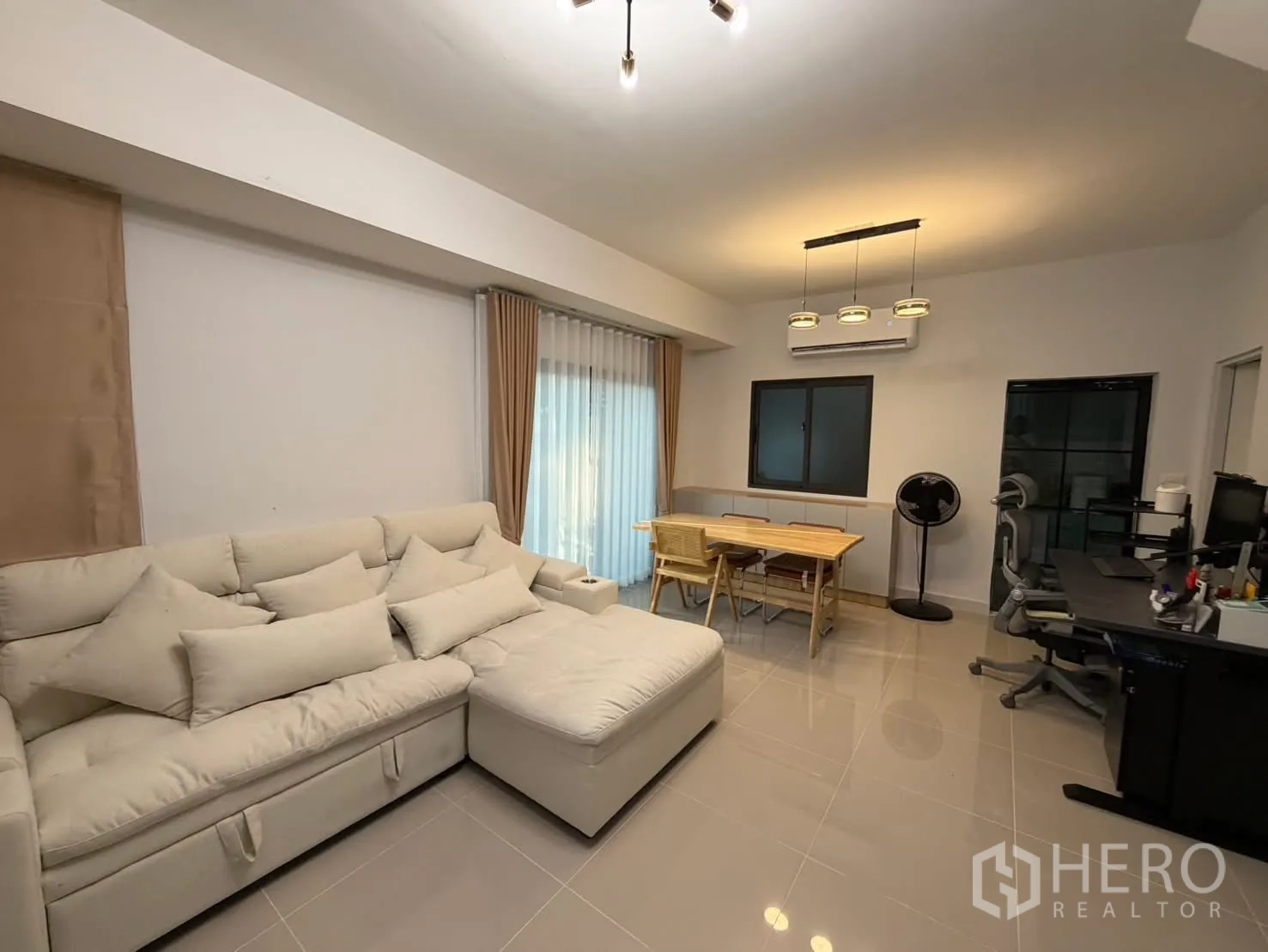 联排别墅 for rent in Bang Phli, Samut Prakan - 客厅配沙发、餐桌与工作台，旁有推拉玻璃门与窗户。