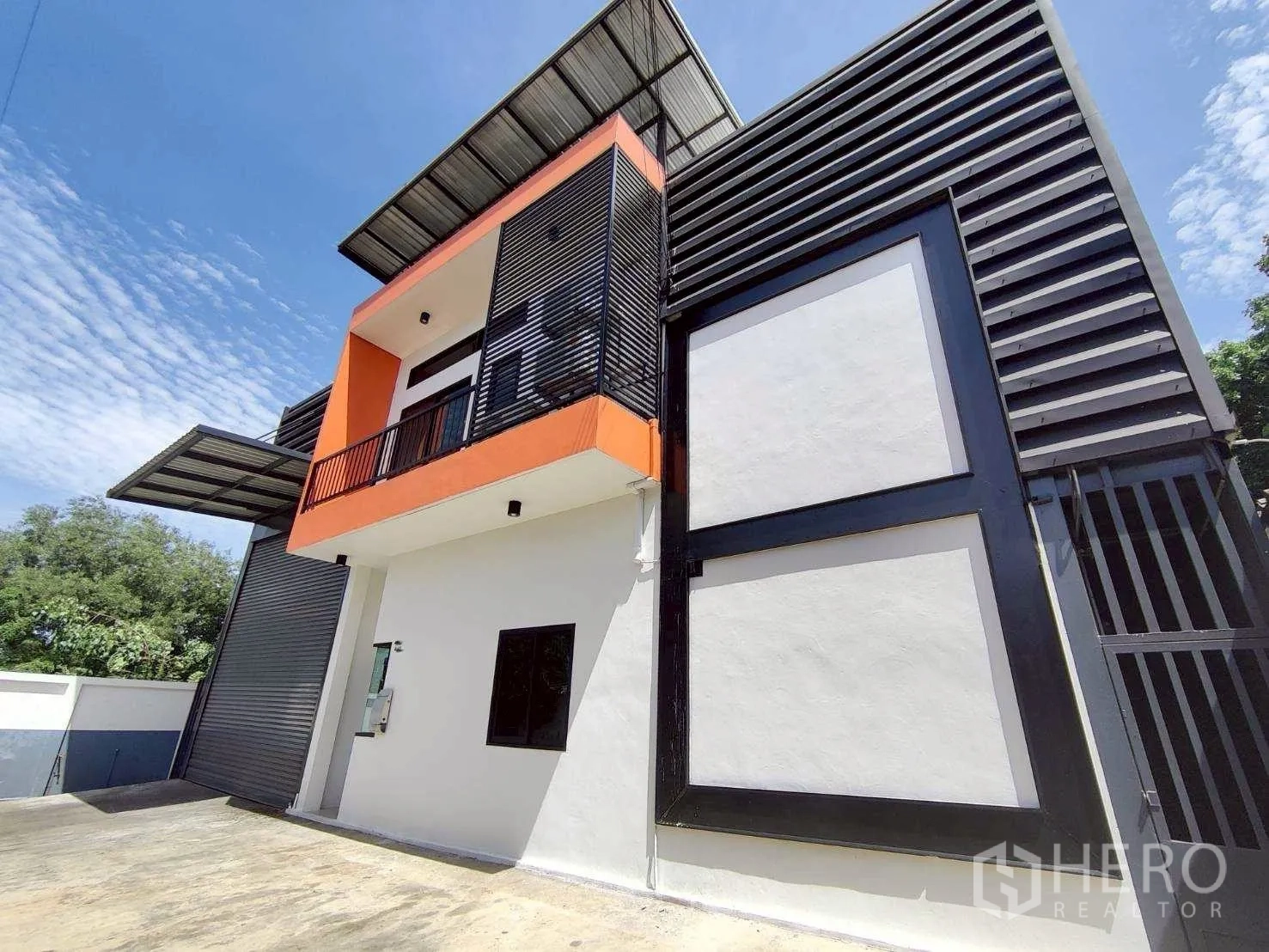 Warehouse for rent in Lam Luk Ka, Pathum Thani - Two-storey warehouse facade with balcony, screened panels, and paved forecourt.
