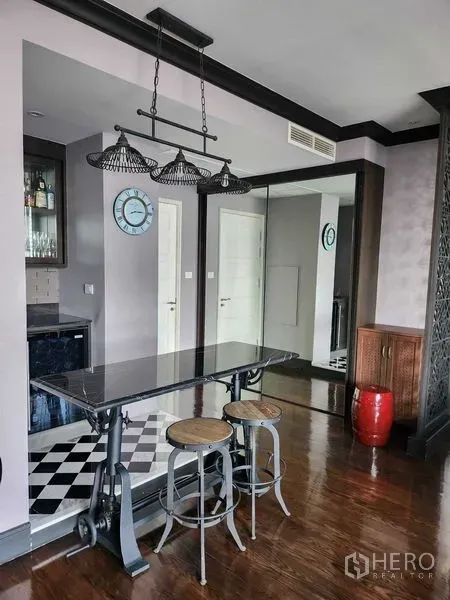 Condominium for sale in Khlong Toei, Bangkok - Breakfast bar with industrial stools and pendant lights beside a mirrored wall.