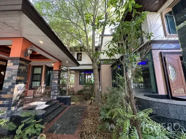 Detached House for sale in Lam Luk Ka, Pathum Thani - Shaded front porch with stone pillars and mature trees at the villa