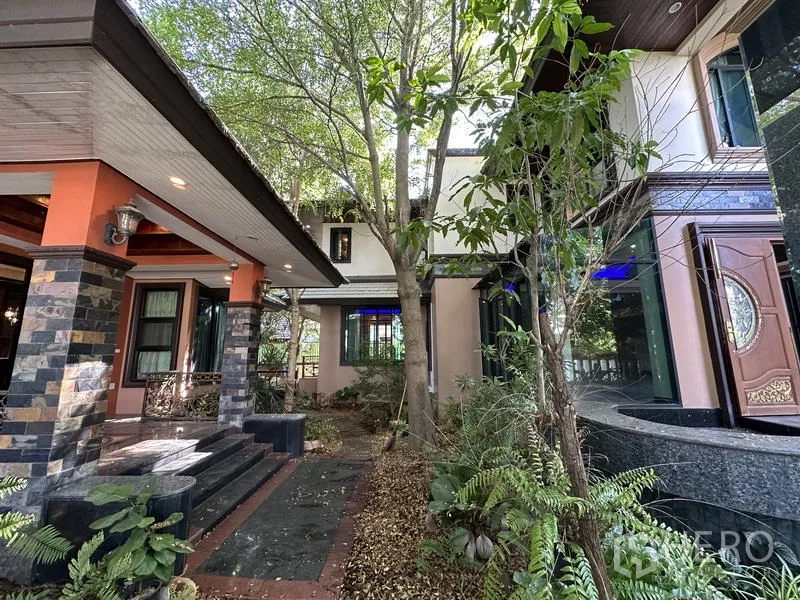 Detached House for sale in Lam Luk Ka, Pathum Thani - Shaded front porch with stone pillars and mature trees at the villa