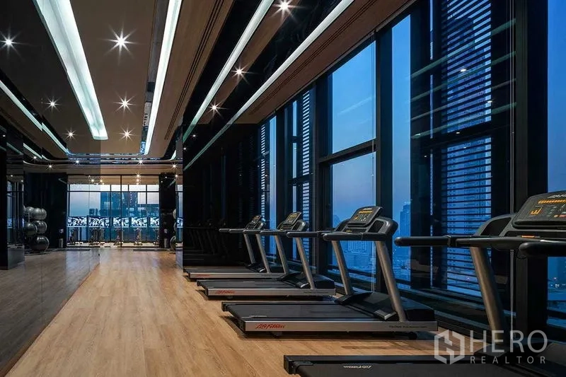 Condominium for rent in Ratchathewi, Bangkok - Modern gym with treadmills and full-height windows overlooking Bangkok.