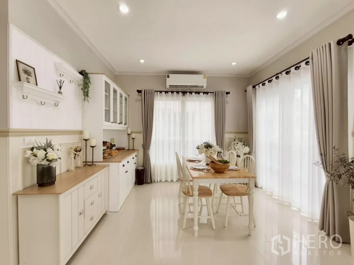 Detached House for rent in Khlong Luang, Pathum Thani - Dining area with white cabinetry, wooden table set and sheer curtains
