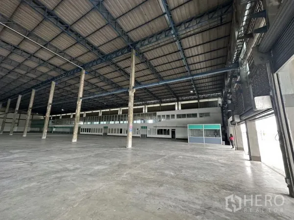 Factory for rent in Bang Sao Thong, Samut Prakan - Interior view toward mezzanine offices and multiple roller shutter entrances.
