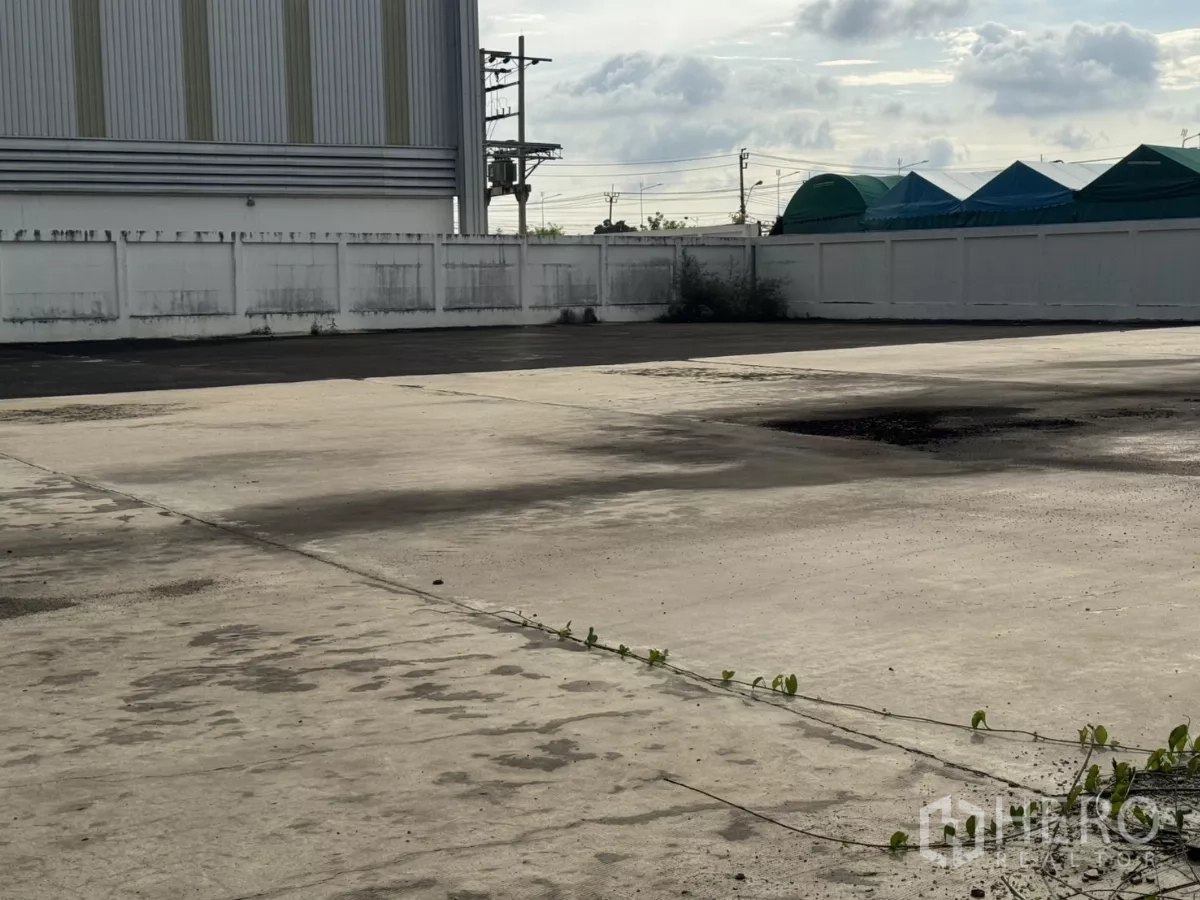Factory for rent or sale in Bang Phli, Samut Prakan - Expansive paved yard within walled compound for truck parking.