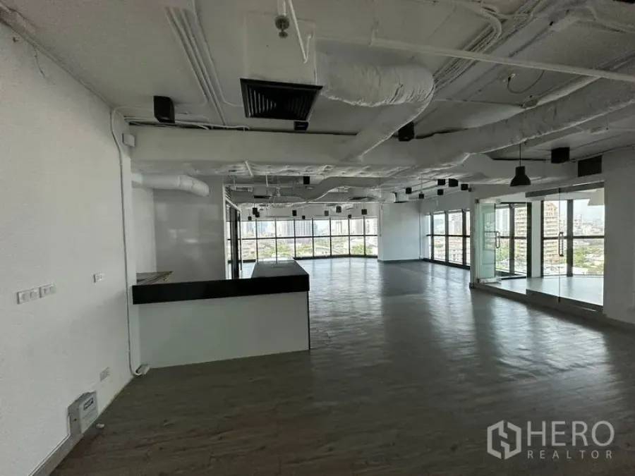 办公空间 出租 - 大型开放办公区，带茶水吧台、外露天花与环景落地窗。
