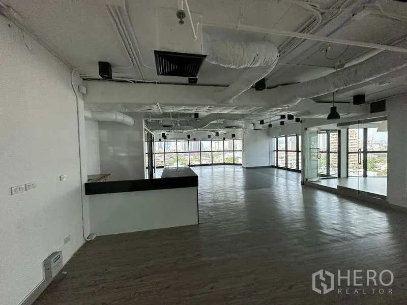 办公空间 出租 - 大型开放办公区，带茶水吧台、外露天花与环景落地窗。