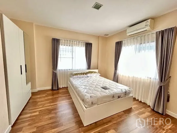 独栋房屋 for rent or sale in Prawet, Bangkok - 宽敞卧室，双人床，木地板，双向采光，白色衣柜与空调。