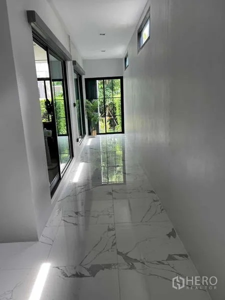Detached House for sale in Khan Na Yao, Bangkok - Bright corridor with glossy marble-look floor tiles and sliding doors opening to greenery.