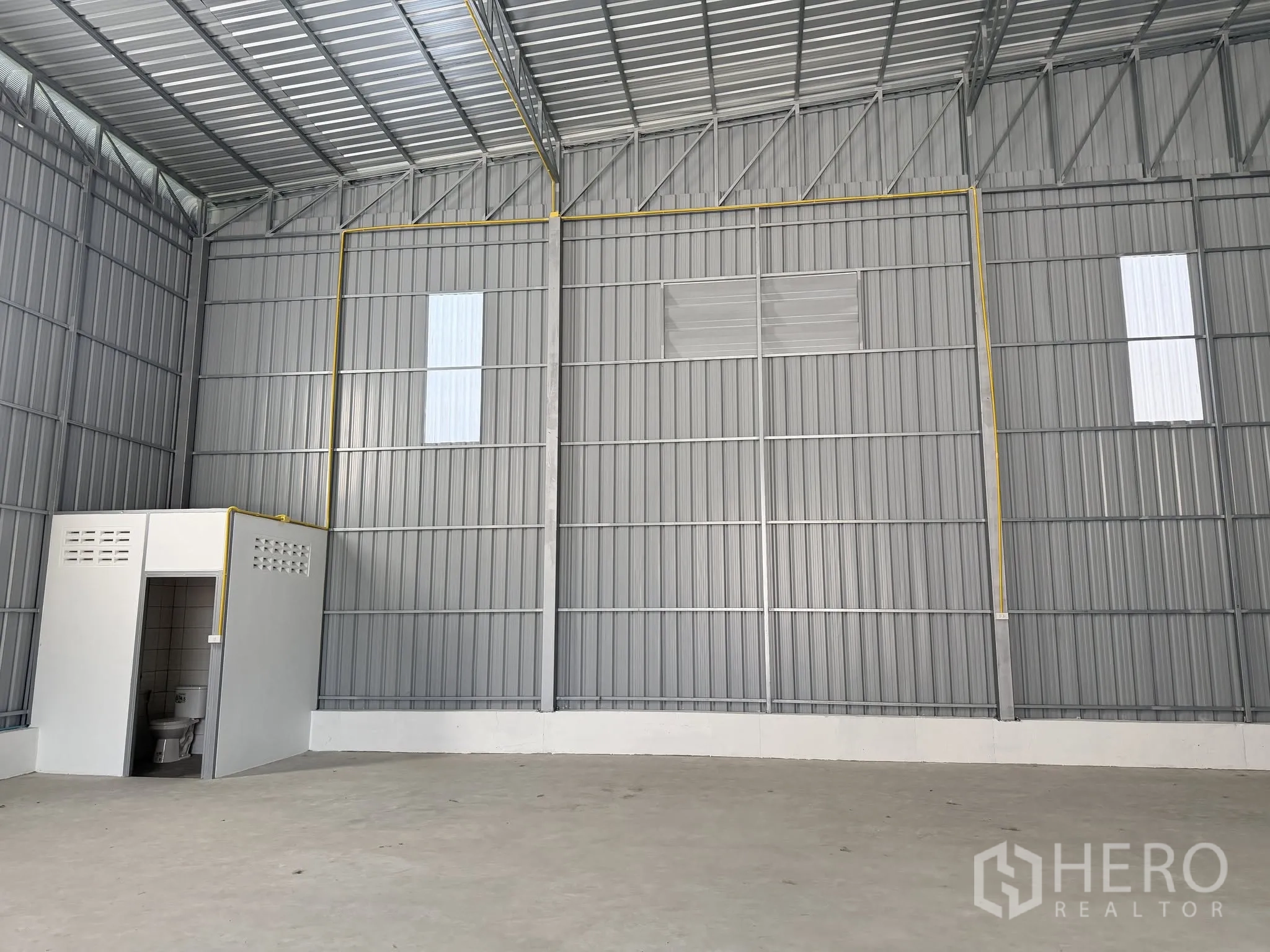 仓库 for rent in Bang Kapi, Bangkok - 仓库内部金属围护与混凝土地面，屋架抬升，并设有内置卫生间。