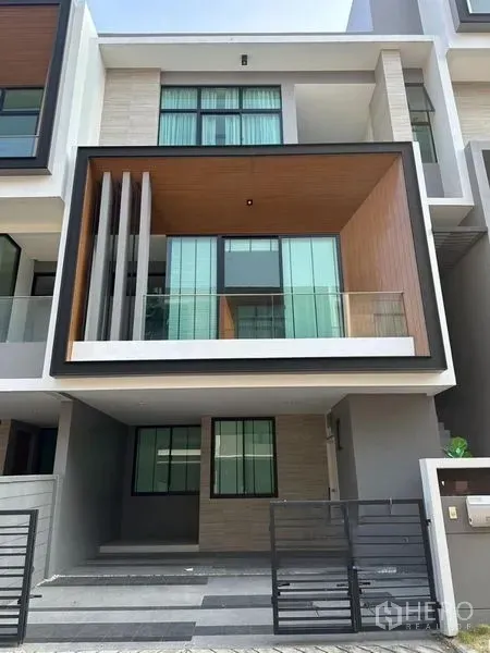联排别墅 出售在Saphan Sung, Bangkok - 三层现代联排别墅外观，玻璃阳台、木质装饰盒与带门车位。