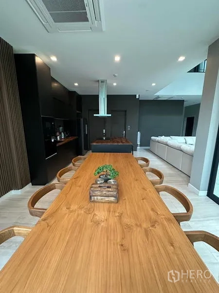 Detached House for rent in Saphan Sung, Bangkok - Open-plan dining and kitchen with long wooden table and island.