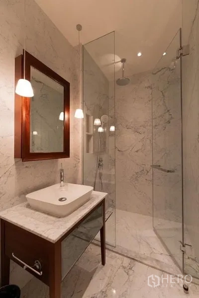 Condominium for rent in Watthana, Bangkok - Compact bathroom with marble vanity, glass shower and pendant lighting.