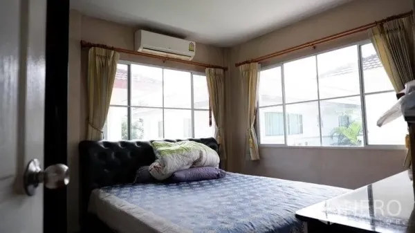 独立式住宅 出租在Prawet, Bangkok - 次卧设转角大窗、窗帘与壁挂空调。