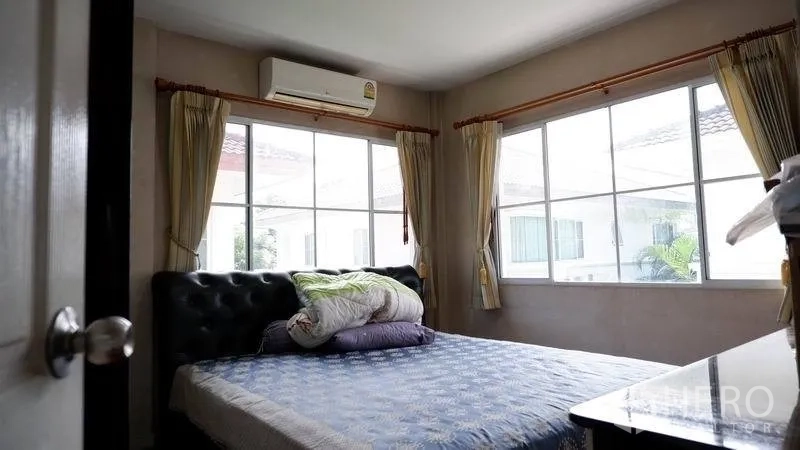 独立式住宅 出租在Prawet, Bangkok - 次卧设转角大窗、窗帘与壁挂空调。