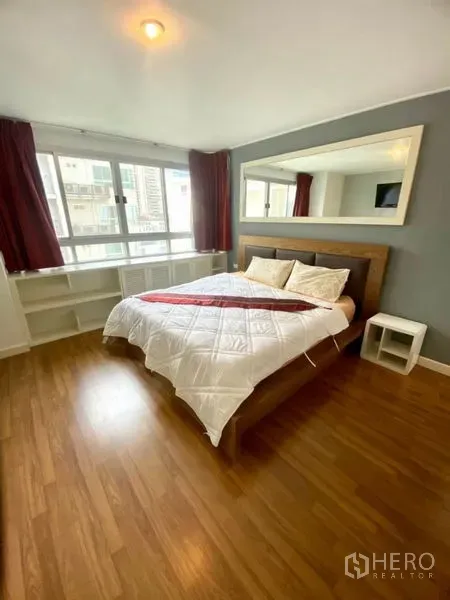 Condominium for rent in Watthana, Bangkok - Spacious bedroom with wood flooring, queen bed, large wall mirror, and wide windows.