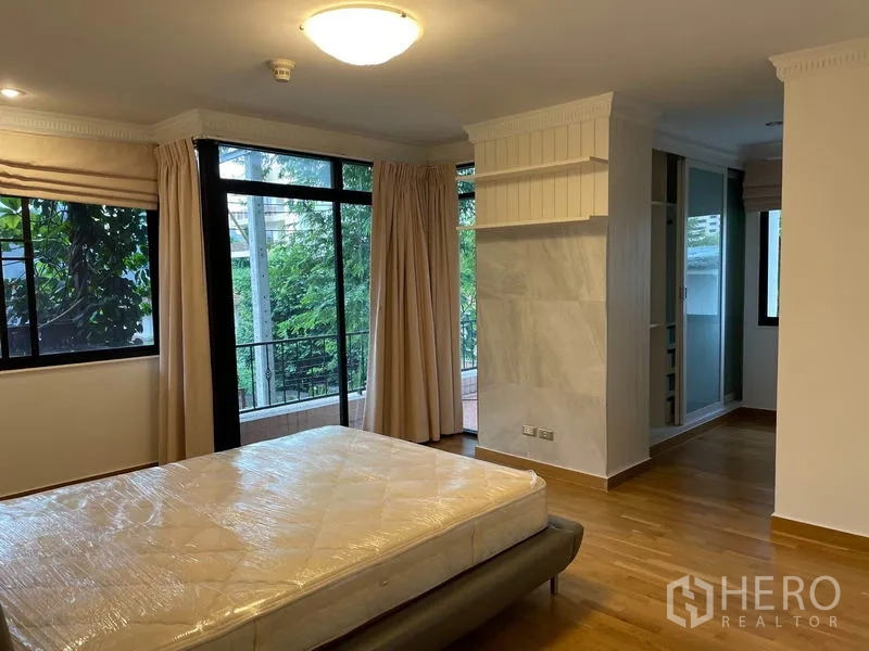 Condominium for rent in Watthana, Bangkok - Primary bedroom with large windows, balcony access and space for a walk-in wardrobe.