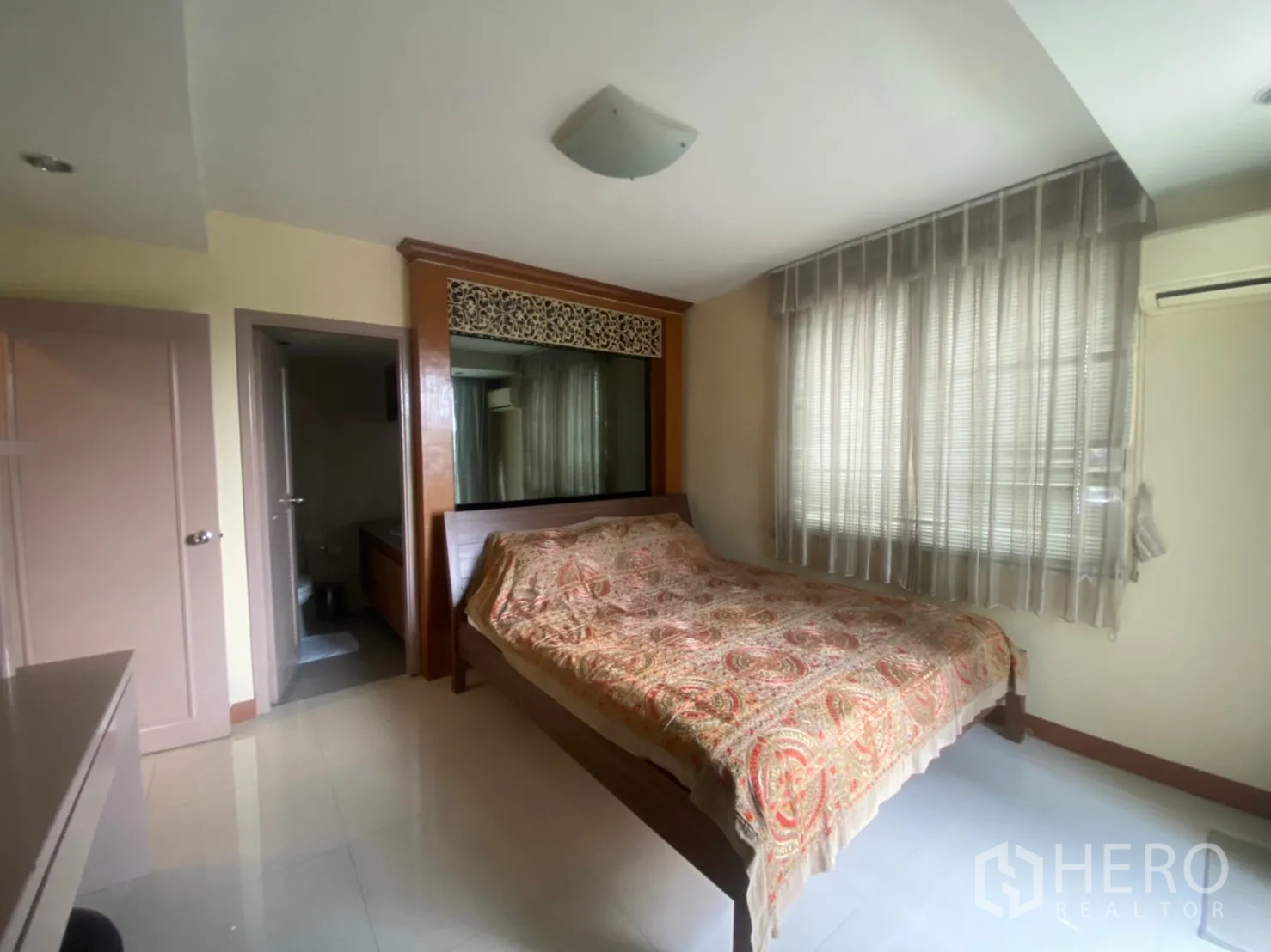 Condominium for rent in Phaya Thai, Bangkok - Cozy bedroom with large window, built-in headboard, and door to an ensuite bathroom.