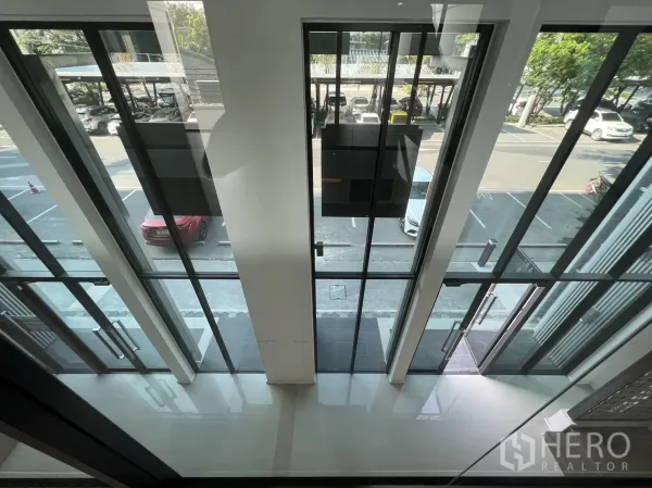 Home Office for rent in Bang Phli, Samut Prakan - View from mezzanine to the full‑height glass storefront and parking area outside.