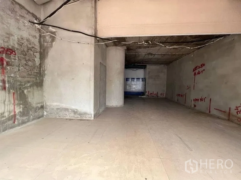 Retail Space for rent - Unfinished retail interior with open-plan layout, high ceiling, central column, and exposed wiring ready for fit-out.