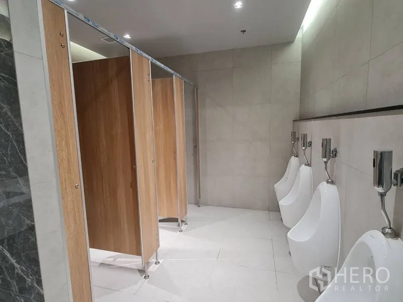 สำนักงาน ให้เช่า - มุมมองห้องน้ำพร้อมประตูห้องสุขาแบบคอกไม้และโถปัสสาวะติดผนัง ผนังและพื้นกระเบื้องโทนอ่อน