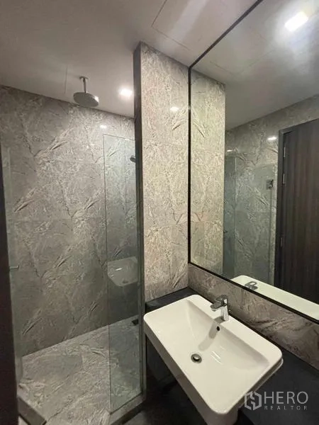 Condominium for rent in Watthana, Bangkok - Contemporary bathroom with glass-enclosed shower, rain head and a large mirror.