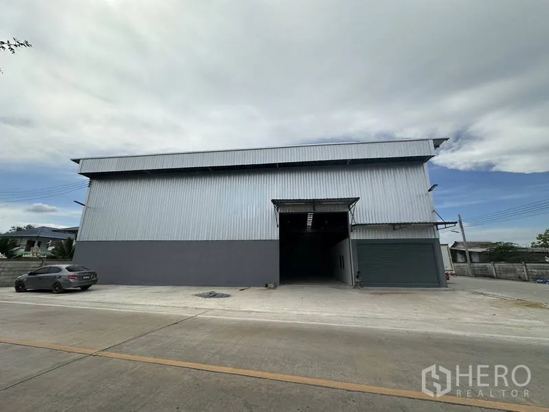Warehouse for rent in Sai Noi, Nonthaburi - Modern corrugated steel warehouse exterior with roller door and driveway in Sai Noi, Nonthaburi.