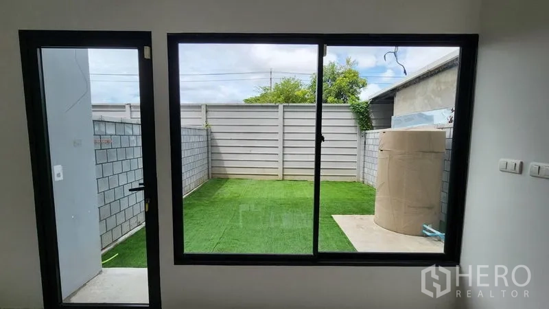 Home Office for rent - View of a small backyard with artificial grass through a glass door.
