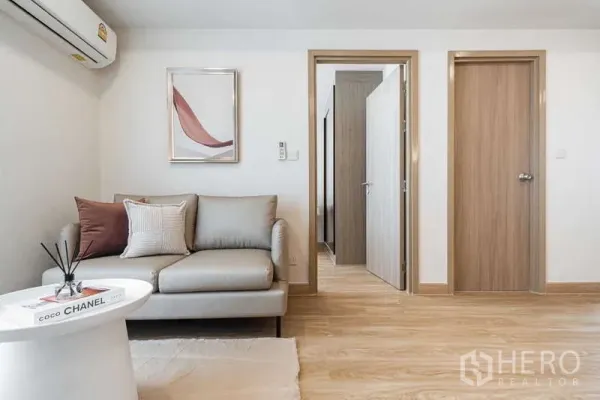 Condominium for rent - Cozy living room with neutral sofa, wall art, and doors leading to bedroom and bathroom.