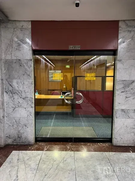 Office Space for rent - Corridor view of glass-front office with stainless handles and reception area inside.