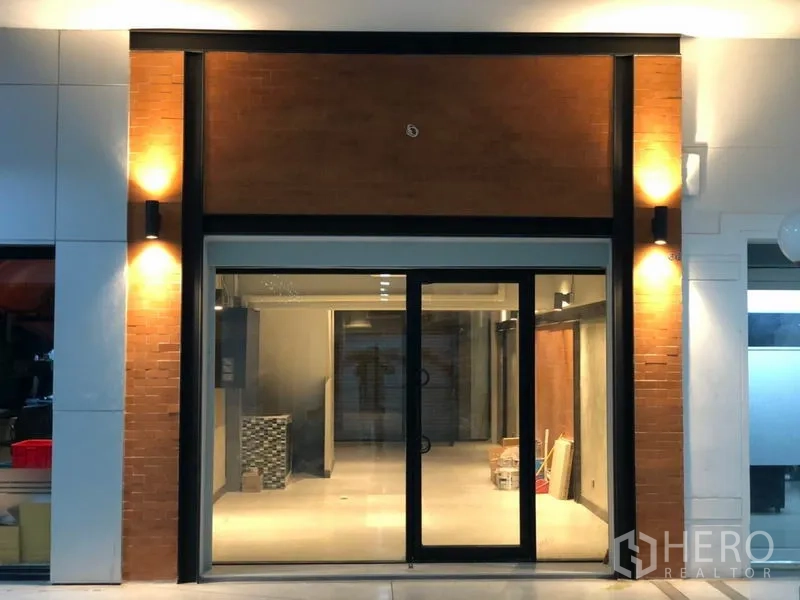 Retail Space for rent in Watthana, Bangkok - Wide shopfront with full-height glazing, warm wall sconces and a visible open interior.