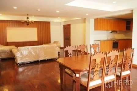 房间 出租在Pathum Wan, Bangkok - 餐区配雕花木椅，邻接客厅与木饰面墙