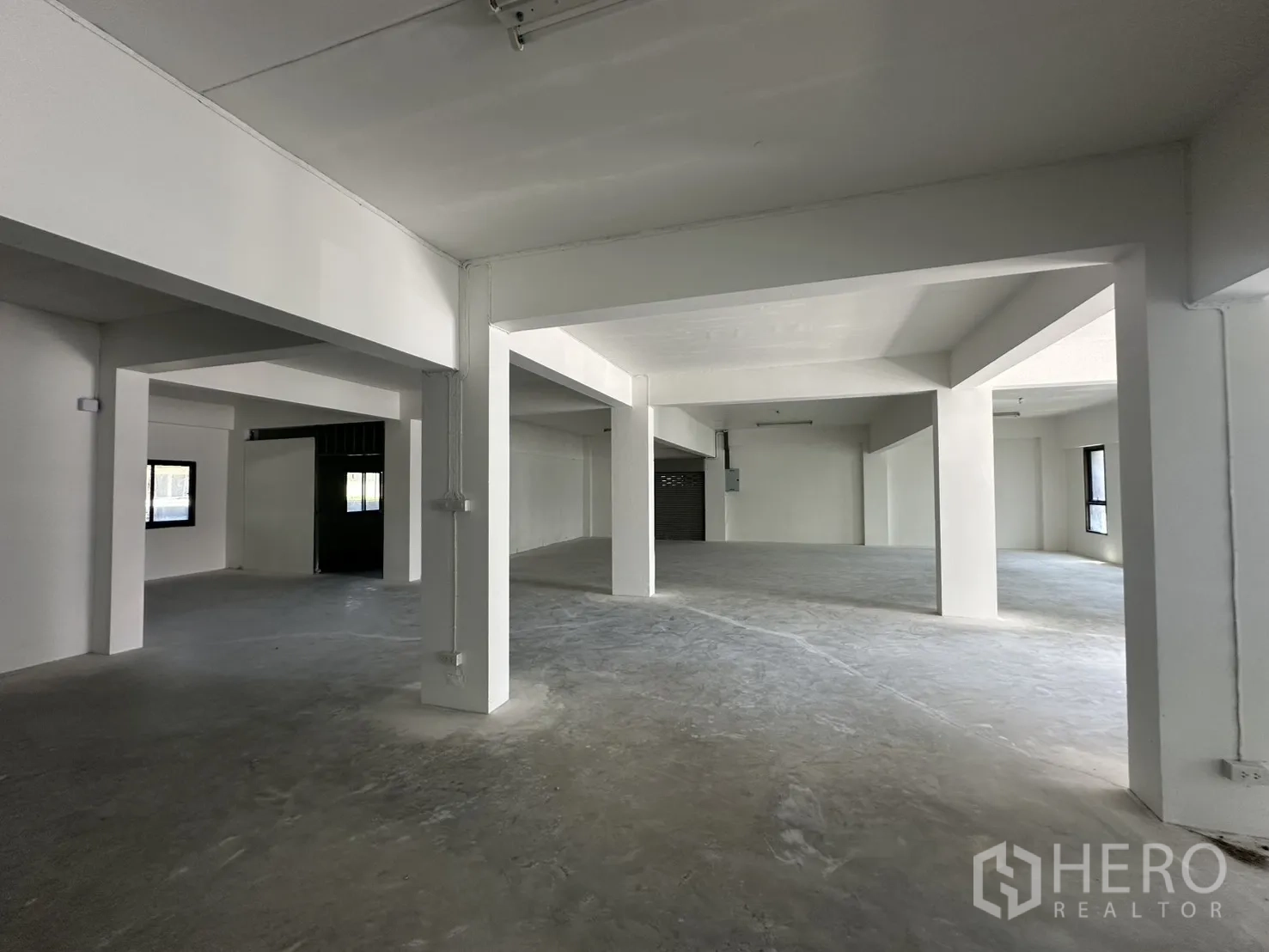 Warehouse for rent in Bang Phli, Samut Prakan - Ground-floor storage area with multiple bays and a roller shutter door.