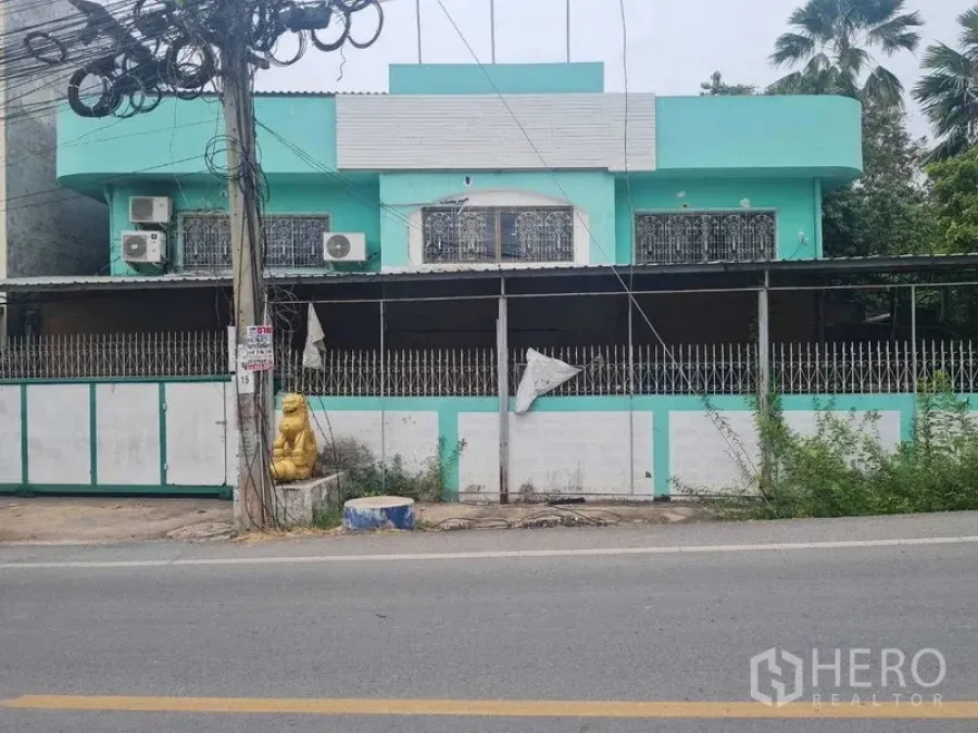 Warehouse for rent in Bang Yai, Nonthaburi - Street view of a turquoise two-storey warehouse building behind a gated fence.