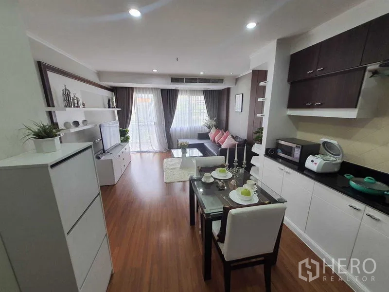 房间 出租在Watthana, Bangkok - 从厨房望向餐桌与客厅，落地窗帘与阳台采光充足。