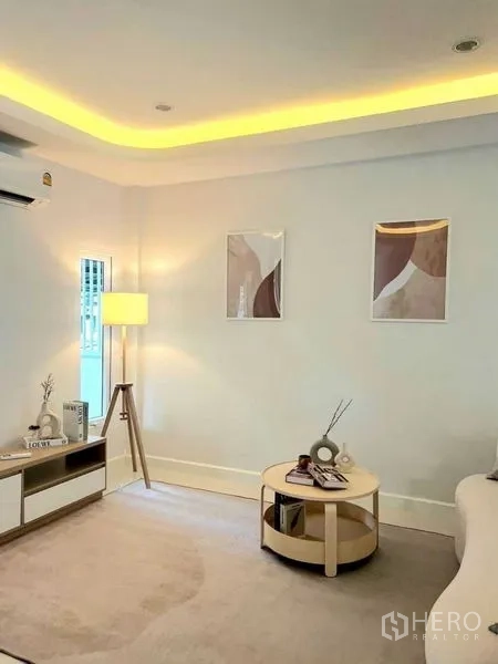 Townhouse for sale in Khlong Toei, Bangkok - Light‑filled lounge with TV console, floor lamp and round coffee table in neutral tones.