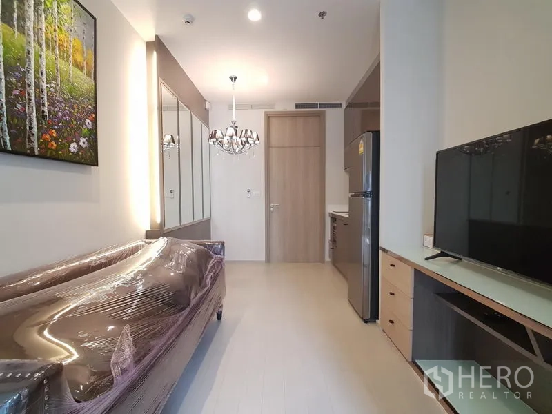 公寓 出租在Pathum Wan, Bangkok - 起居区设电视柜与吊灯，旁边是紧凑厨房