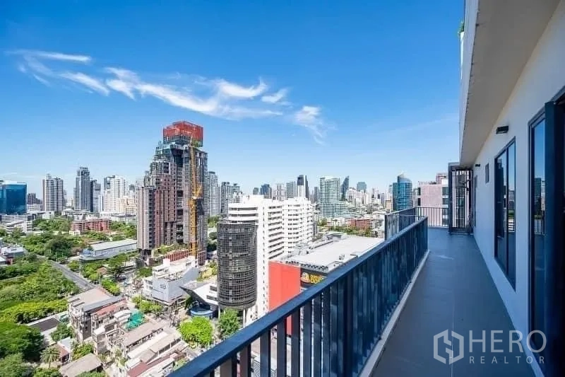 Condominium for sale - Long balcony with railings overlooking the Bangkok skyline under a clear blue sky.
