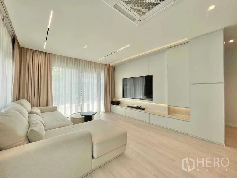 บ้าน ให้เช่าในBang Phli, Samut Prakan - ห้องนั่งเล่นผนังบิลท์อินวางทีวี ไฟดาวน์ไลท์และม่านโปร่ง